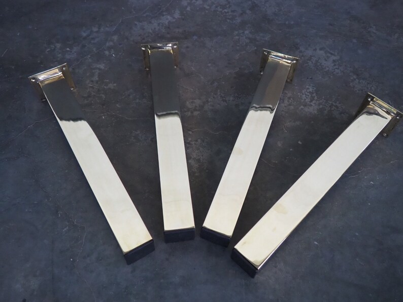 Four polished gold metal table legs with square bases