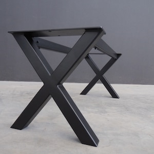 May include: Black metal table base with an X-shaped design. The base is made of thick, sturdy metal and has a black powder coat finish.