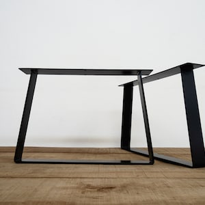 Pode incluir: Duas pernas de mesa de metal preto com um design simples e moderno. As pernas são anguladas e têm uma forma retangular.