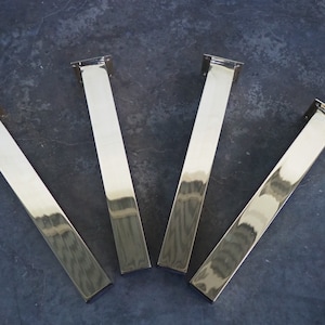 Four silver metal table legs with a rectangular shape and a polished finish.