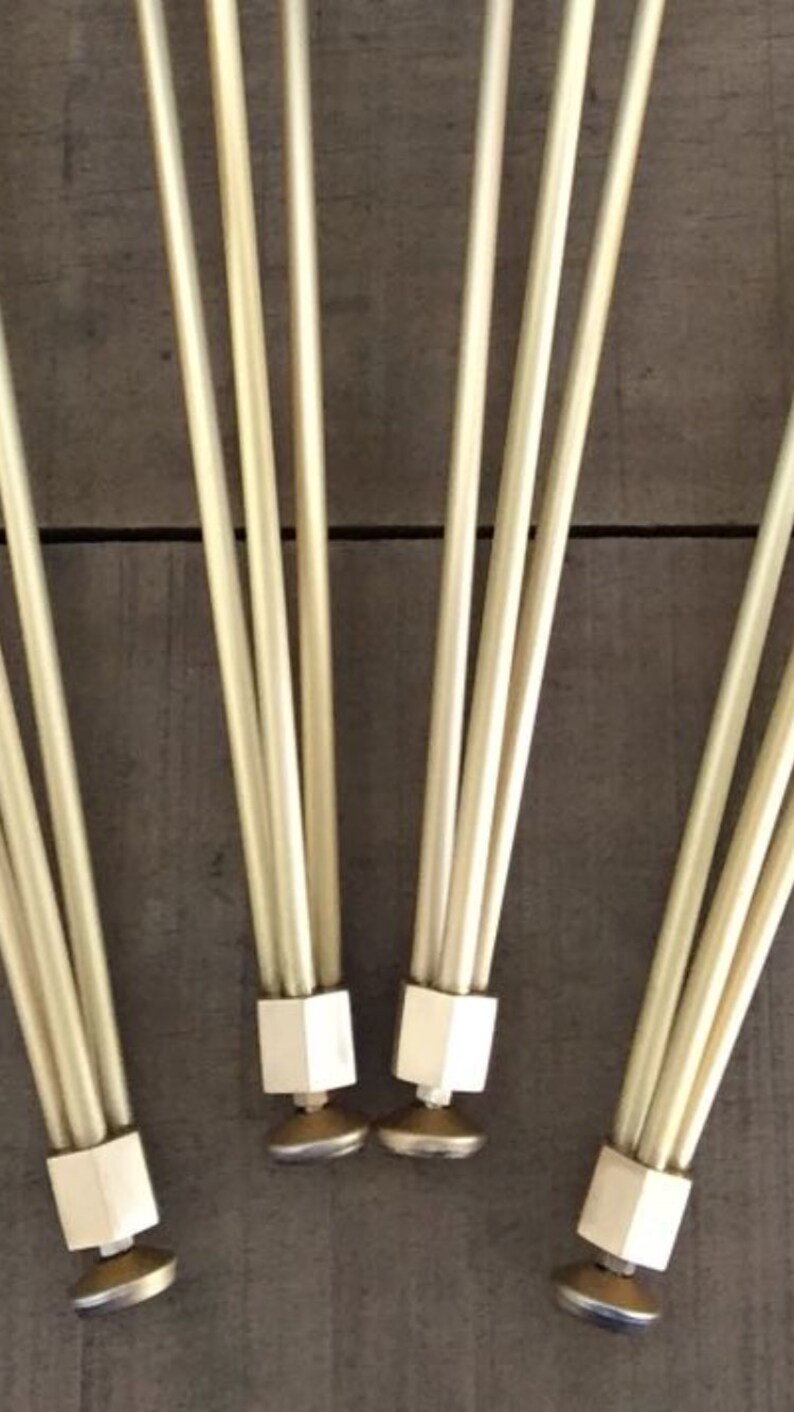 May include: Four sets of gold metal legs with a hexagonal base and a round foot. The legs are arranged in a fan shape.