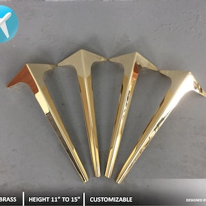 Pode incluir: Quatro pernas de mesa de metal dourado com forma triangular. As pernas medem de 28 a 38 cm de altura. 4 LEGS | BRASS | HEIGHT 11" TO 15" | CUSTOMIZABLE