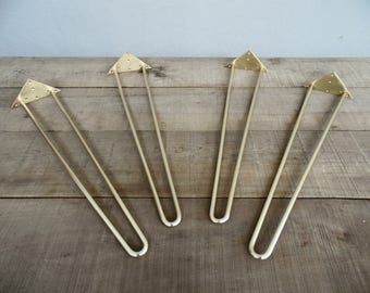 May include: Four gold metal hairpin legs for furniture. The legs are 12 inches long and have a triangular base.