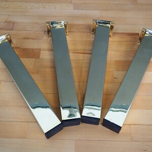 Four gold metal table legs with black rubber feet