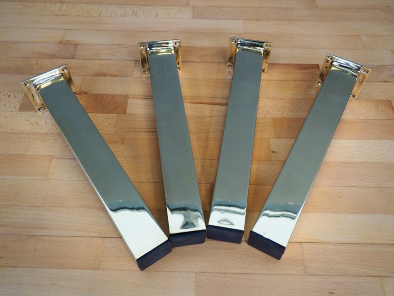 Four gold metal table legs with black rubber feet