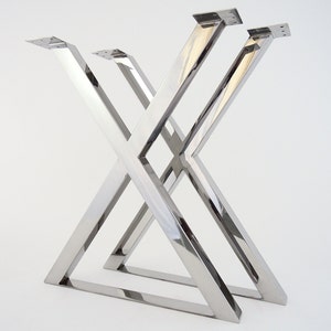 Op de afbeelding: Drie zilveren metalen tafelpoten in een X-vorm.