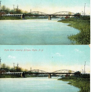 May include: A vintage postcard depicting two arched bridges spanning the Clyde River in Clyde, N.Y. The image shows a calm river scene with green vegetation on the banks and a light blue sky. The text "Clyde River showing Bridges, Clyde, N. Y." is printed at the top.