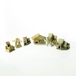 May include: A set of five miniature houses made of brown clay with thatched roofs. The houses are arranged in a semi-circle on a white surface.