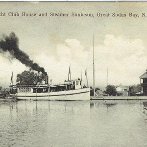 May include: Vintage black and white postcard featuring the Yacht Club House and Steamer Sunbeam on Great Sodus Bay, N.Y. The image shows a steamboat emitting a large plume of smoke, with buildings along the shoreline.