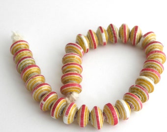 May include: A strand of colorful paper beads with alternating red and yellow stripes. The beads are strung on a white cord and are arranged in a circle.