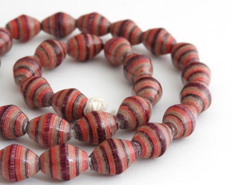 May include: A strand of red and brown paper beads. The beads are made of rolled paper and have a striped pattern.