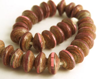 May include: A strand of brown and pink paper beads. The beads are made of rolled paper and have a layered, textured look.