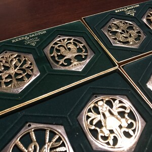 May include: Set of six silver and gold Christmas ornaments in individual boxes. Each ornament features a different design from the 12 Days of Christmas song. The boxes are lined with green velvet.