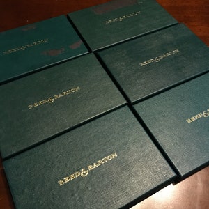May include: Six green gift boxes with gold lettering that reads "Reed & Barton".