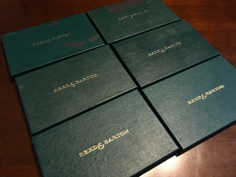 May include: Six green gift boxes with gold lettering that reads "Reed & Barton".