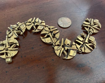 May include: A gold-toned bracelet made of linked, circular, geometric shapes.
