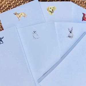 May include: A set of six blank note cards with different dog breeds illustrated on each card. The cards are white with a light blue tint and have a subtle texture. The dogs are illustrated in black and white and are all different breeds.