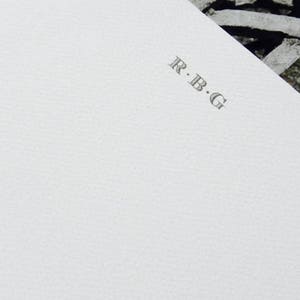 May include: A white card with the text "R.B.G." printed in gray.