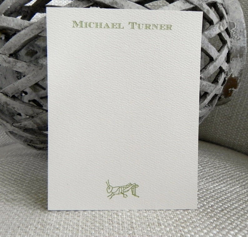 May include: A white card with a green grasshopper illustration and the name "MICHAEL TURNER" printed in green at the top.