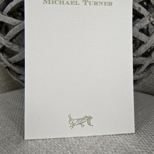 May include: A white card with a green grasshopper illustration and the text "MICHAEL TURNER" printed in green at the top.