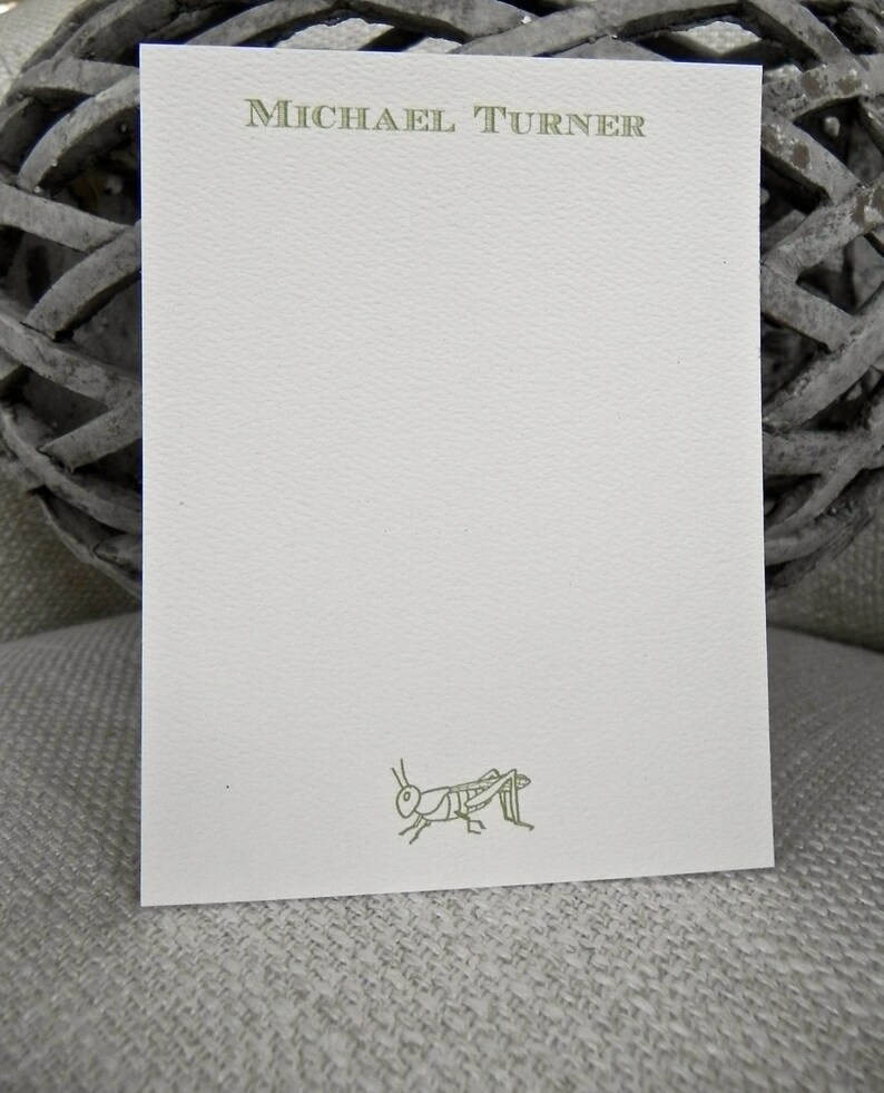 May include: A white card with a green grasshopper illustration and the text "MICHAEL TURNER" printed in green at the top.