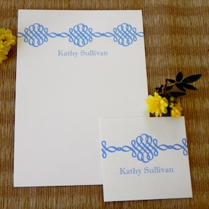 Peut inclure: Deux cartes de correspondance blanches avec des bordures d&eacute;coratives bleues et le nom "Kathy Sullivan" imprim&eacute; sur chacune. La plus grande carte est une feuille de papier pleine, tandis que la plus petite carte est une carte pli&eacute;e.
