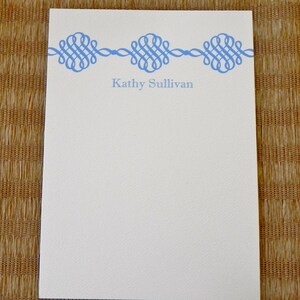 Peut inclure: Un bloc-notes blanc avec une bordure d&eacute;corative bleue et le nom "Kathy Sullivan" imprim&eacute; en bleu en haut.