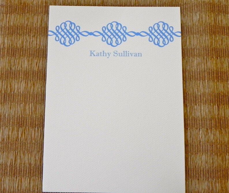 Peut inclure: Un bloc-notes blanc avec une bordure d&eacute;corative bleue et le nom "Kathy Sullivan" imprim&eacute; en bleu en haut.