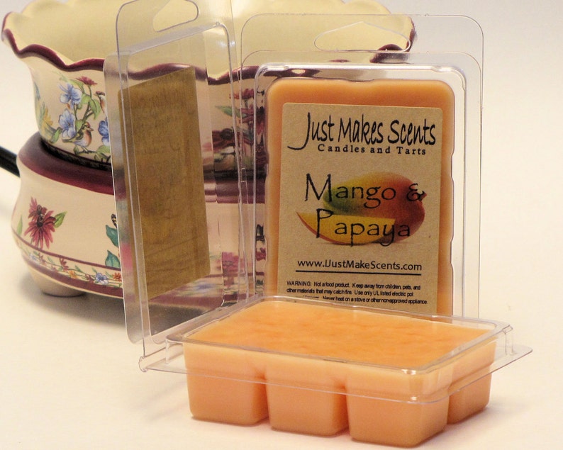 May include: A clear plastic container with a wax melt inside. The wax melt is a light orange color and has a label that says "Just Makes Scents Candles and Tarts" and "Mango & Papaya".