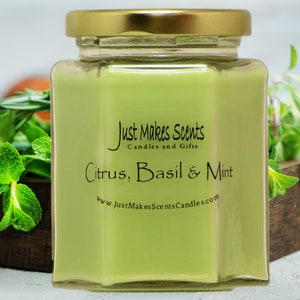 May include: A green glass jar candle with a gold lid. The label reads "Just Makes Scents Candles and Gifts" and "Citrus, Basil & Mint" with the website "www.justmakescentscandles.com".