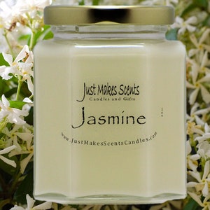 May include: A clear glass jar candle with a gold lid. The candle is labelled "Just Makes Scents Candles and Gifts" and "Jasmine". The jar is surrounded by white jasmine flowers.