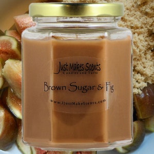 May include: A glass jar candle with a brown sugar and fig scent. The jar is labelled "Just Makes Scents Candles and Tarts" and "Brown Sugar & Fig". The jar is surrounded by brown sugar and fresh fig slices.