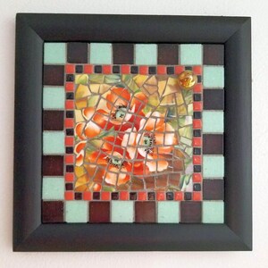 May include: Square mosaic art piece with a black frame. The mosaic features a central image of orange poppies, surrounded by a border of brown, mint green, and red tiles. A small, round, gold-colored embellishment is in the upper right corner.