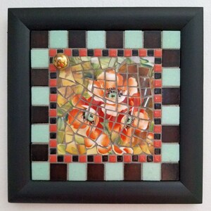 May include: Square mosaic art piece with a black frame. The mosaic features orange flowers with green leaves. The border includes a checkerboard pattern of brown, mint green, and red tiles. A gold-colored knob is in the upper left corner.