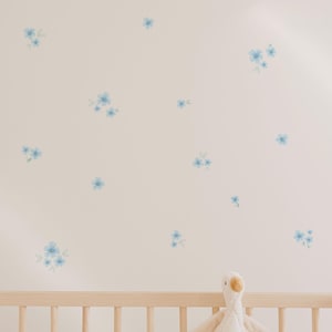 Pared blanca de dormitorio infantil decorada con vinilos decorativos y adhesivos de alta calidad en forma de flores en color azul. Vinilo de alta calidad - Nicolasito.es
White wall of a kids bedroom decorated with high-quality decorative adhesive vinyl stickers in the shape of blue flowers. Premium vinyl – Nicolasito.es