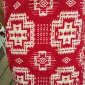 May include: Red and white patterned blanket with a geometric design. The blanket has a soft, fuzzy texture.