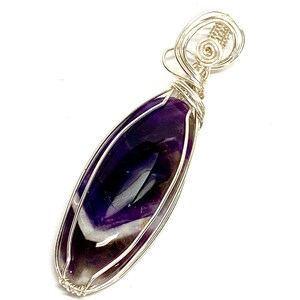 May include: A silver wire wrapped pendant featuring a purple and white amethyst gemstone.