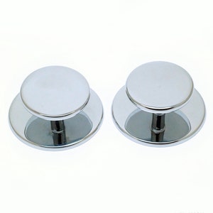 Op de afbeelding: Twee verchroomde ronde kastknoppen met een verhoogde ronde bovenkant en een korte steel. De knoppen zijn ontworpen voor gebruik op meubels of kasten.