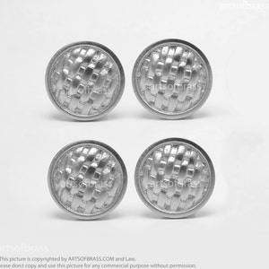 Può includere: Quattro pomelli per armadietti color argento con un design a trama intrecciata. Ogni pomello è rotondo con un bordo leggermente rialzato. I pomelli sono disposti in una formazione quadrata su sfondo bianco. Il marchio "artsofbrass" è visibile.