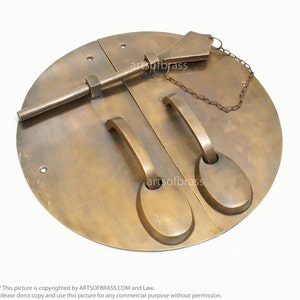 May include: A pair of antique brass door handles with a round plate and a latch. The handles have a simple design and are attached to a chain.