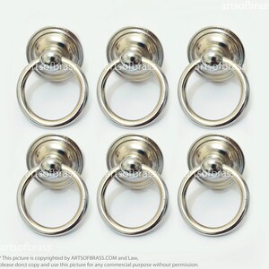 Może przedstawiać: Sześć srebrnych uchwytów do drzwi szafki w kształcie pierścienia z okrągłą podstawą.