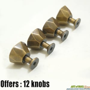 Może przedstawiać: Cztery antyczne mosiężne gałki do szafek o geometrycznym wzorze. Gałki mają kwadratową podstawę i spiczasty wierzchołek. Oferta: 12 gałek.