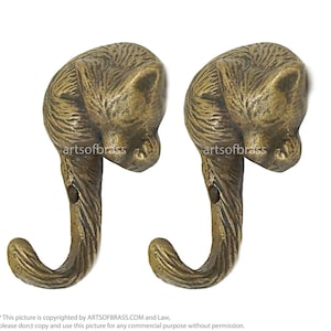 Puede incluir: Dos ganchos de metal de color dorado con forma de gatos durmiendo. Los ganchos están diseñados para montarse en una pared.
