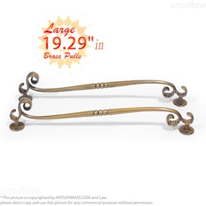 May include: Two antique brass cabinet pulls with a decorative scroll design. Each pull is 19.29 inches long.