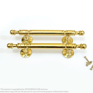 May include: A pair of gold door handles with a decorative design. The handles are attached to round plates and come with screws.