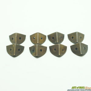 May include: Ten antique brass corner brackets with two holes each. The brackets are in a slightly tarnished condition, giving them a vintage look.