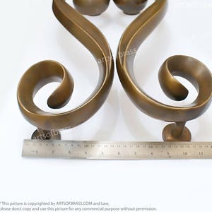 May include: A pair of ornate brass door handles with a scrolled design. The handles are approximately 9 inches long.
