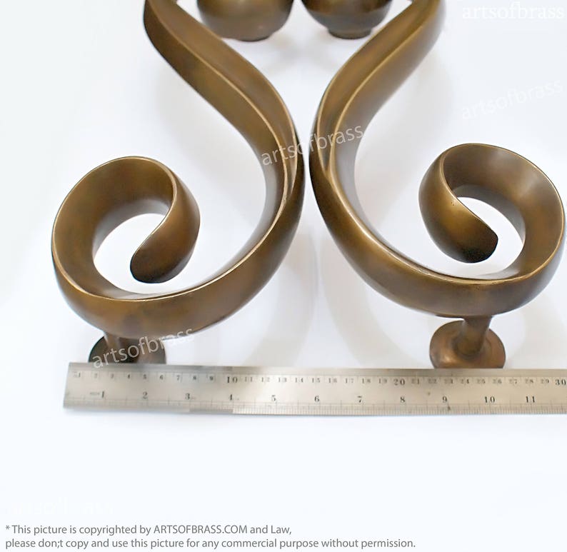 May include: A pair of ornate brass door handles with a scrolled design. The handles are approximately 9 inches long.