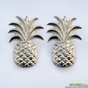 May include: A pair of silver pineapple door knobs. The pineapple is a popular tropical fruit and a symbol of hospitality.