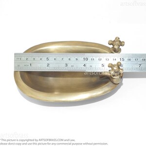 May include: A small, oval-shaped brass bathtub with a faucet on each end. The bathtub is 15 inches long and is made of solid brass.
